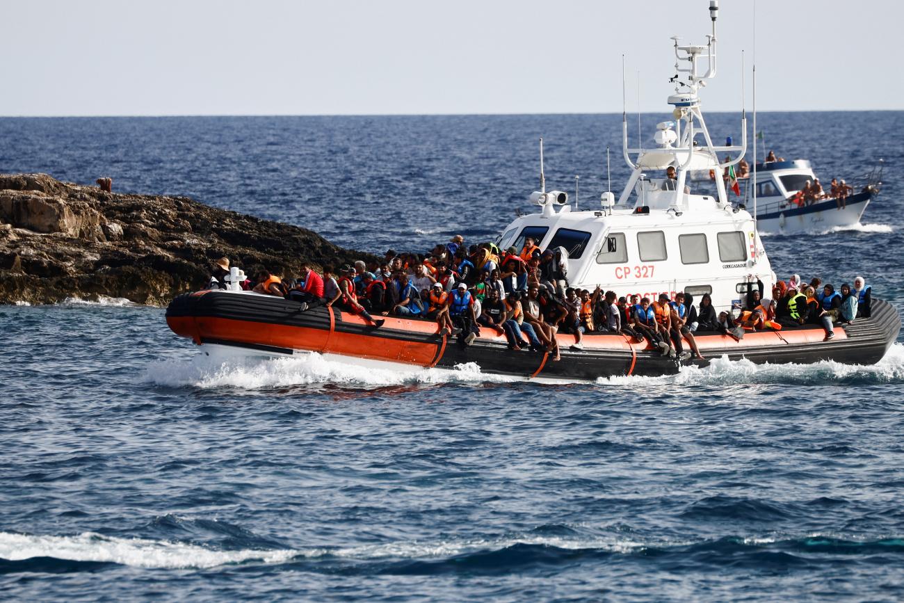 A boat full of migrants floats in the water.