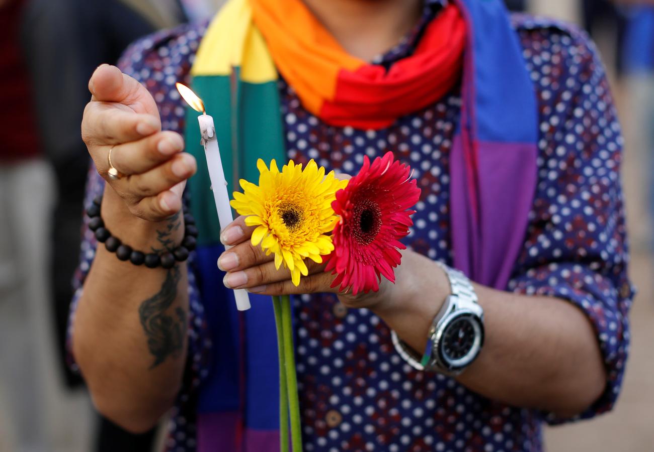 A participant holds a candle during a vigil in memory of the victims of the Pulse gay nightclub shooting.