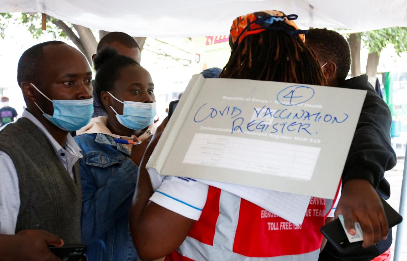 A health-worker talks to civilians before a COVID-19 vaccine at a makeshift tent