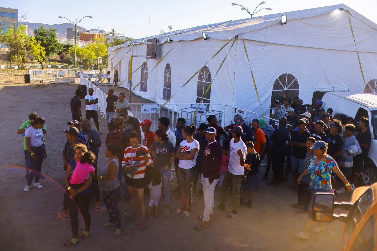 Migrants stand near a makeshift shelter set up by the local government.