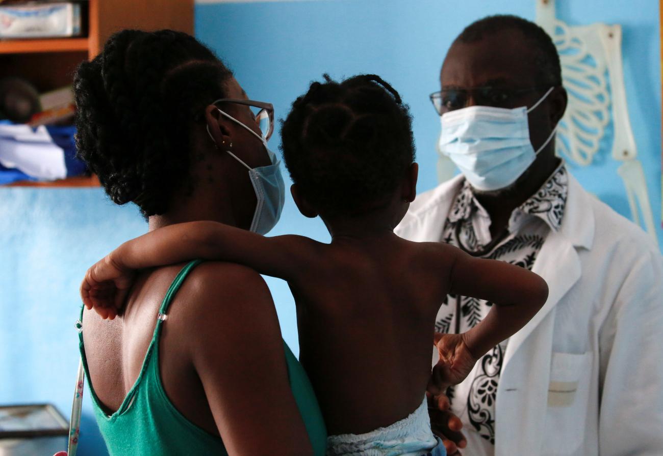 A doctor prepares to take care of a girl with malaria at his clinic.