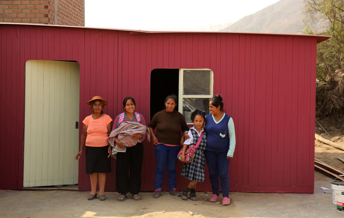Simeona Mosquera and her daughters pose for a picture in front of their new house donated by NGO Partners in Health.