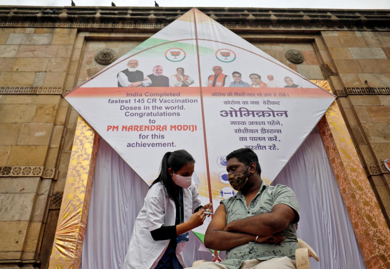 A man receives a dose of vaccine against COVID-19 in front of a giant kite, installed to mark administering 1.45 billion COVID-19 vaccine doses in India, in Ahmedabad, India, on January 6, 2022.