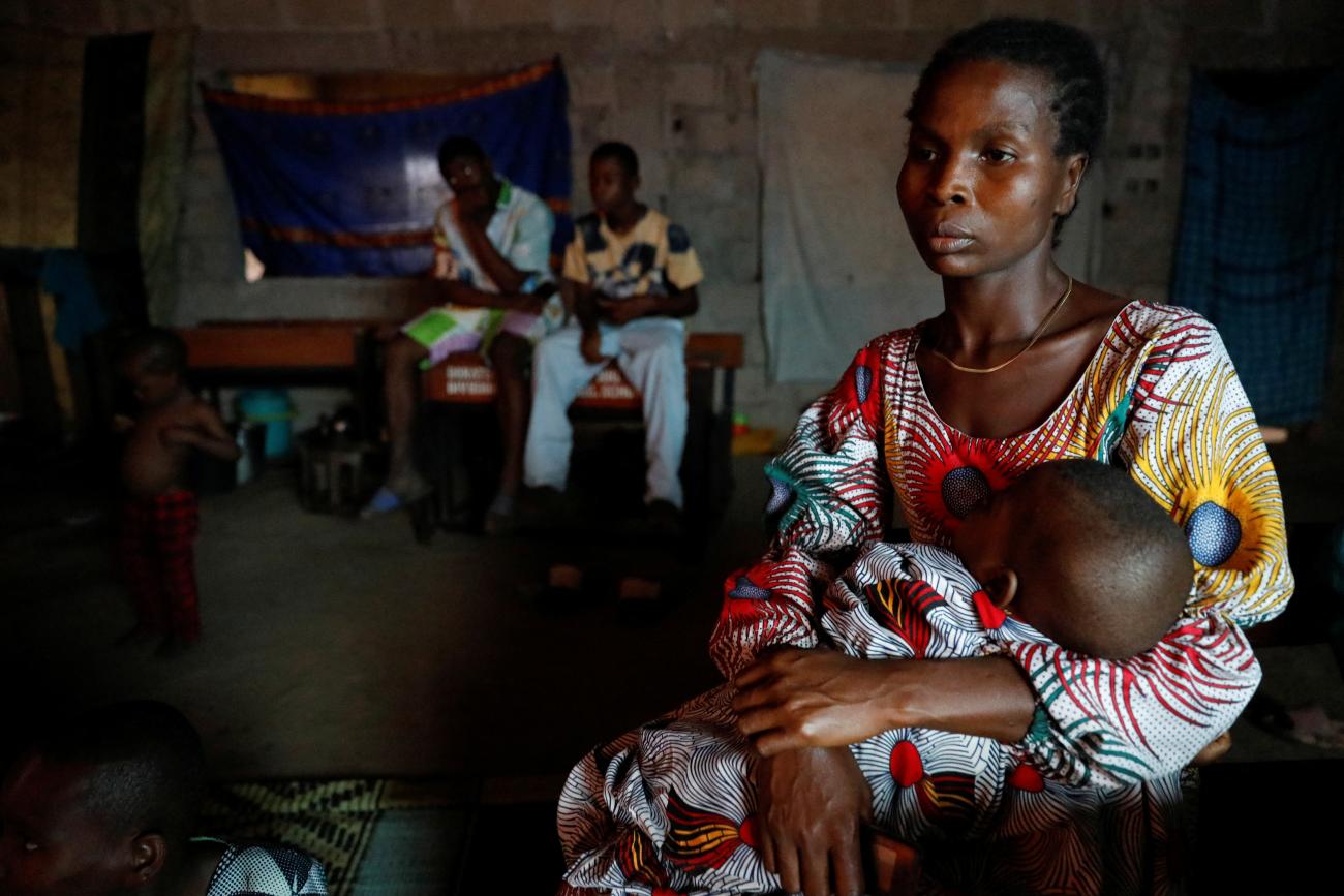 A tailor who became a flood victim, carries her baby at a school converted to relief camp in Ogbogu.