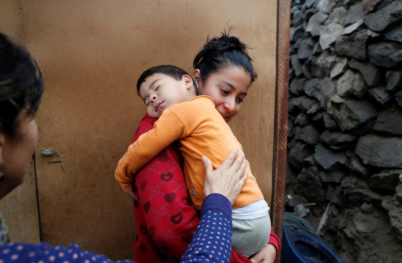 Margarita Valle, a health worker with Partners in Health talks to Carmen Zumaeta who carries her two year old son