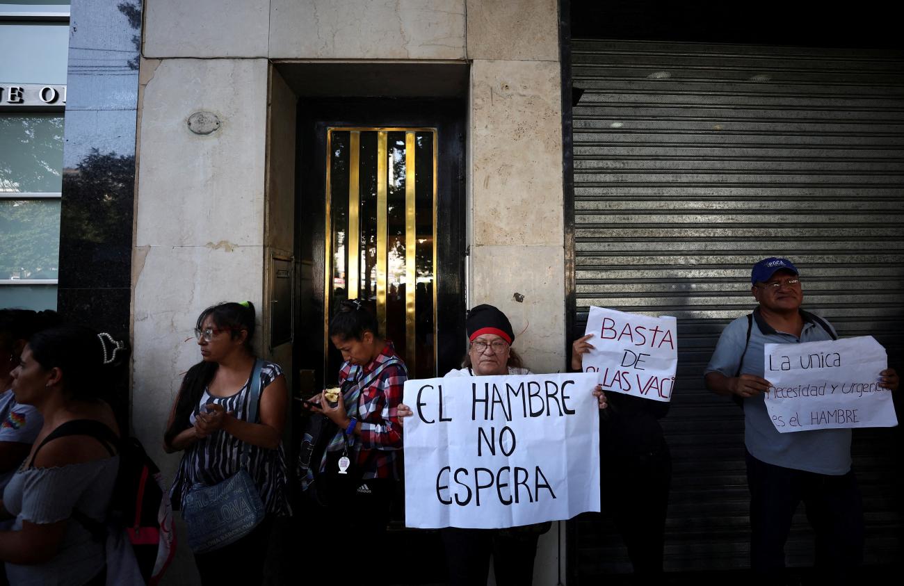 A demonstrator holds a placard that reads "The hunger doesn't wait."