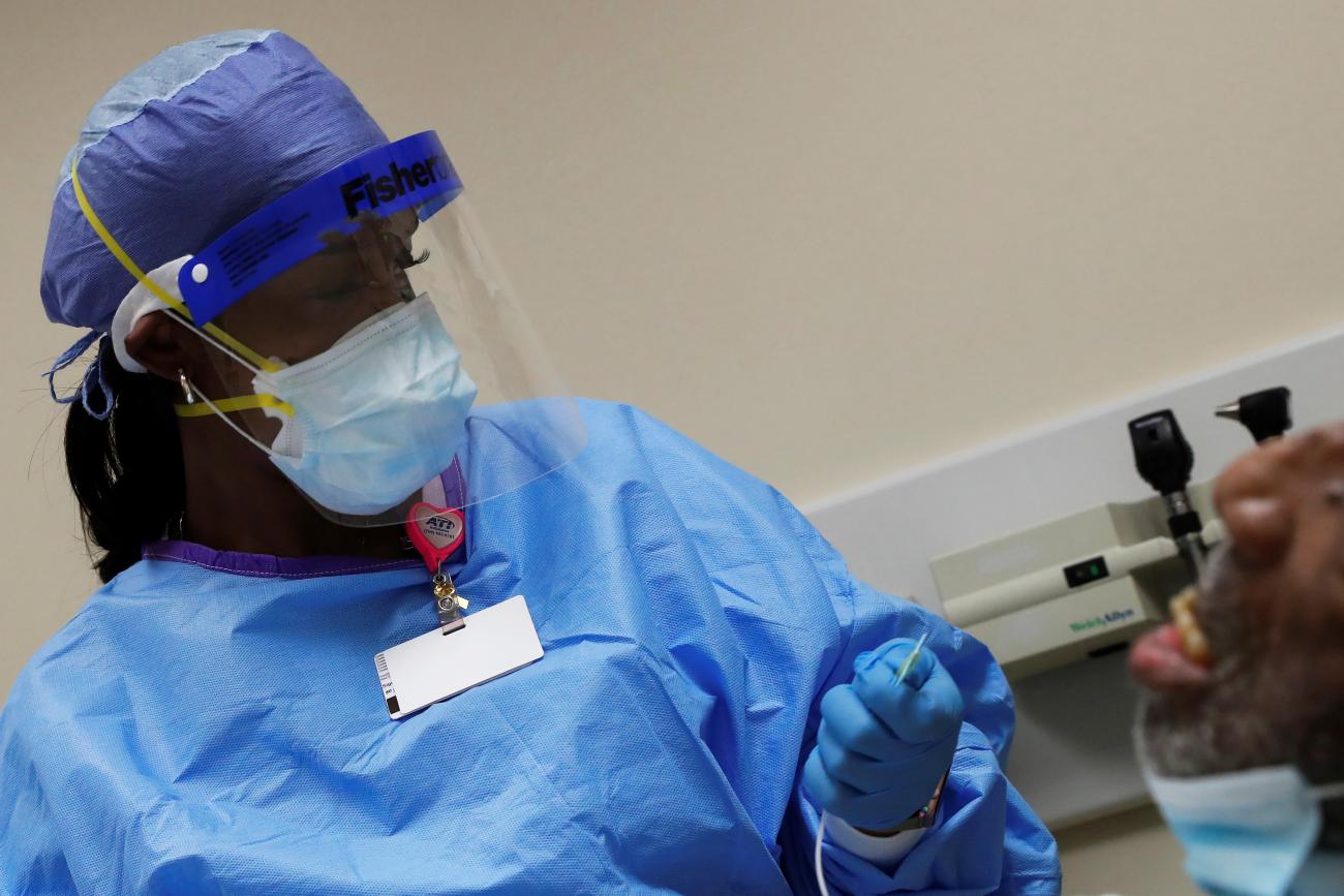 A doctor runs tests on a patient being monitored for COVID-19.