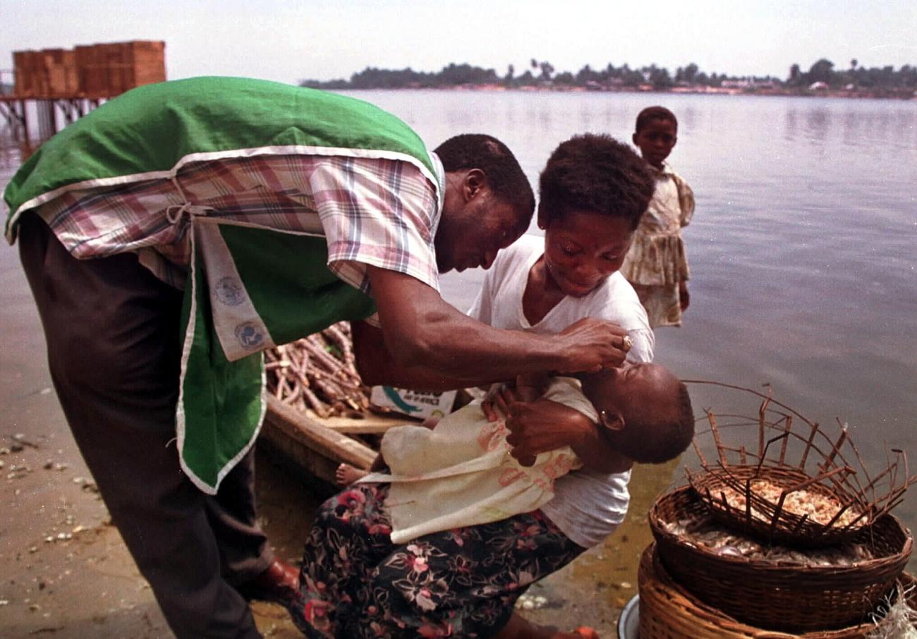 A Nigerian health official immunizes a baby against polio along the bank of the Ibeshe river in Lagos, on June 4, 2001.