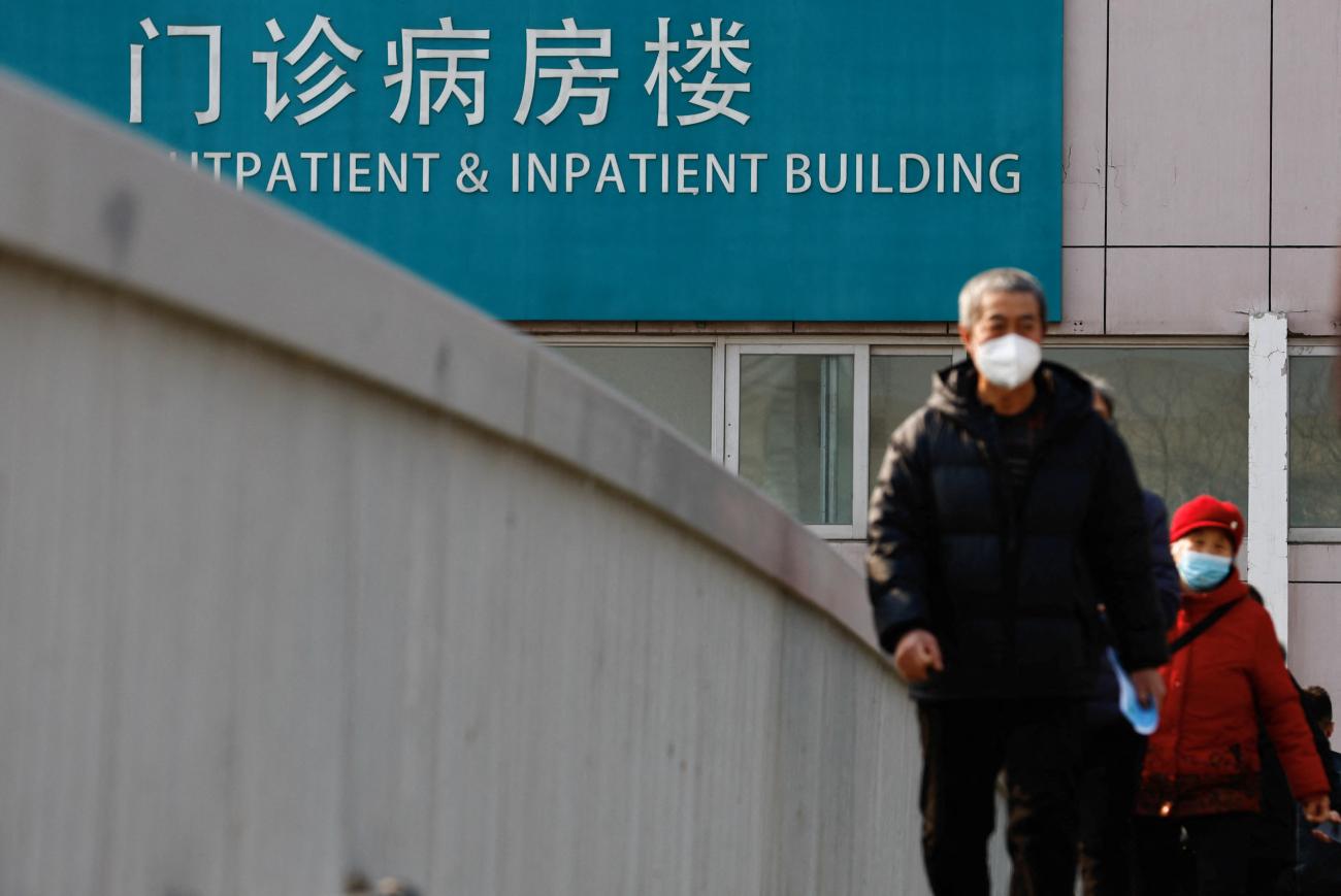 People walk on an overpass near a hospital.