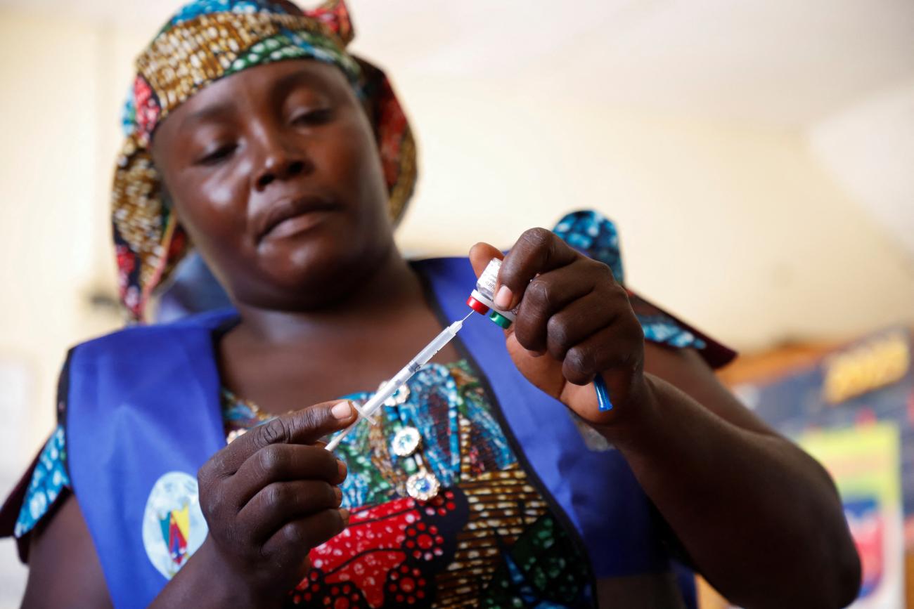 A nurse prepares to administer a malaria vaccine to an infant at the health center.