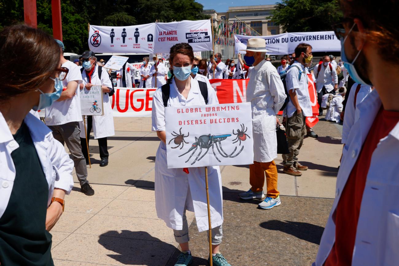 Members of Doctors for XR (Extinction Rebellion) carry signs as they gather to present WHO Director General Tedros Adhanom Ghebreyesus with a letter urging him to take action on climate change, in Geneva, Switzerland, May 29, 2021.