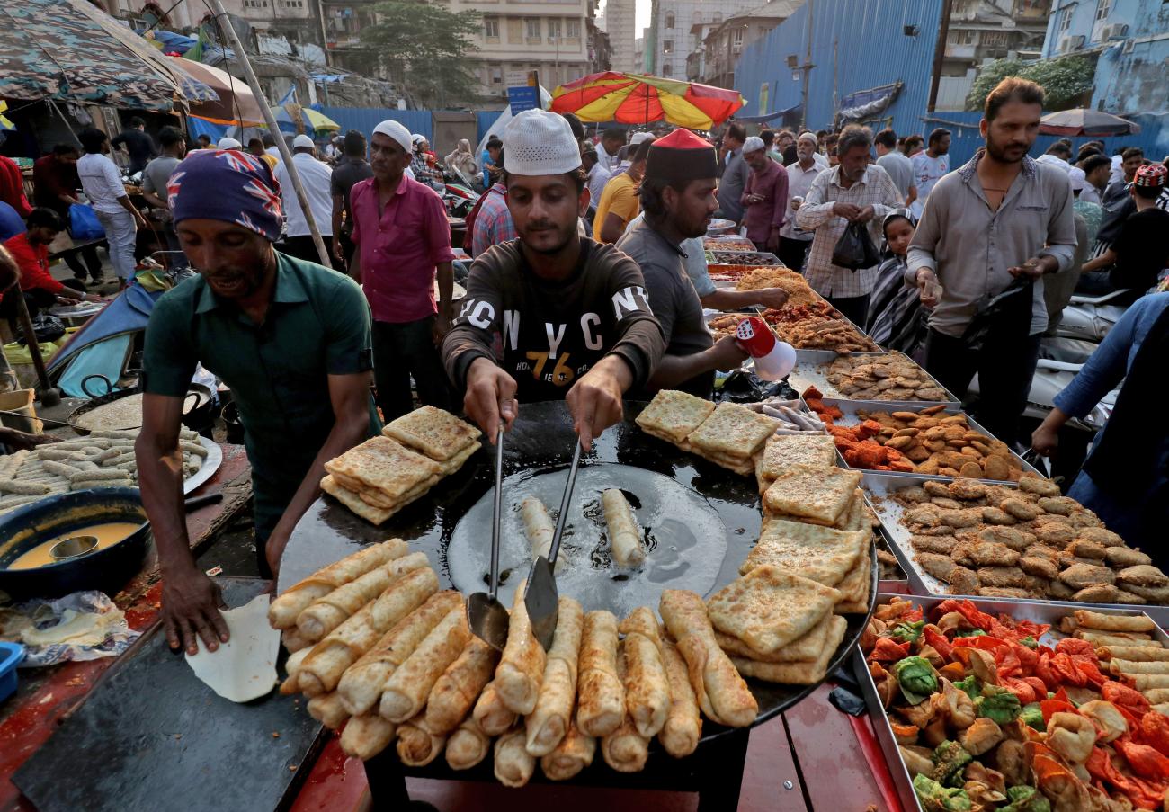 A man fries snacks while waiting for people to purchase it.