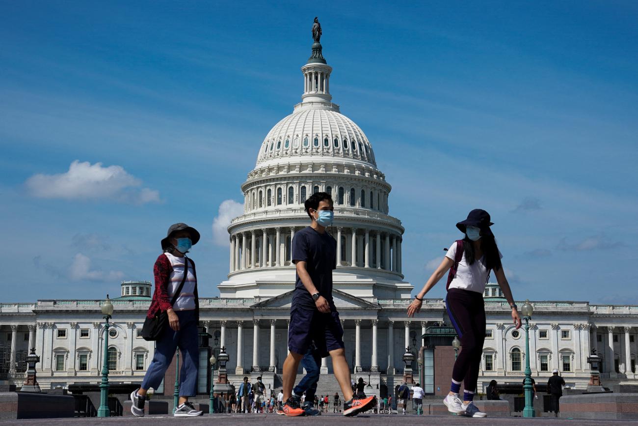 People wearing masks for protection against COVID-19 walk past the U.S. Capitol 