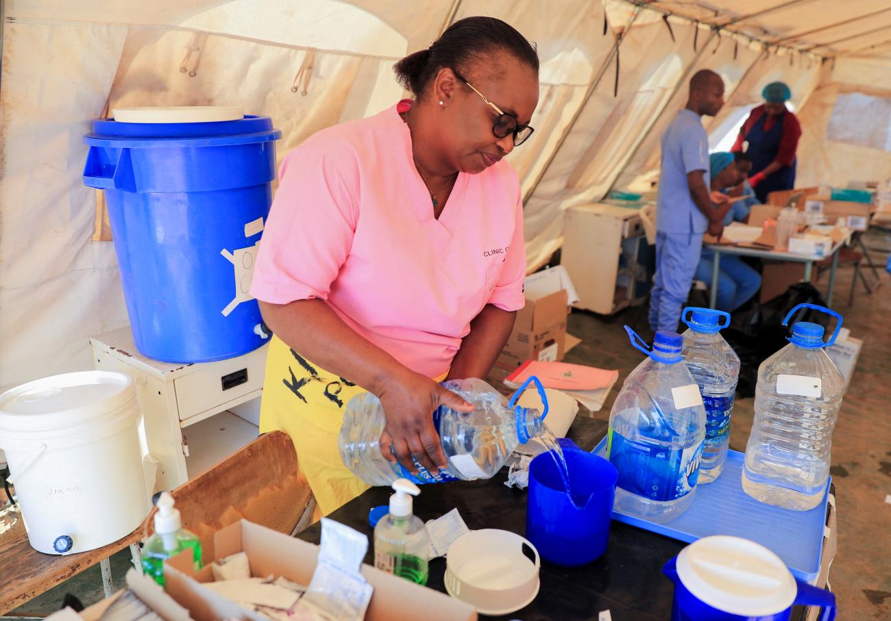 A health worker prepares a solution inside a tent for cholera patients at Kuwadzana Polyclinic.