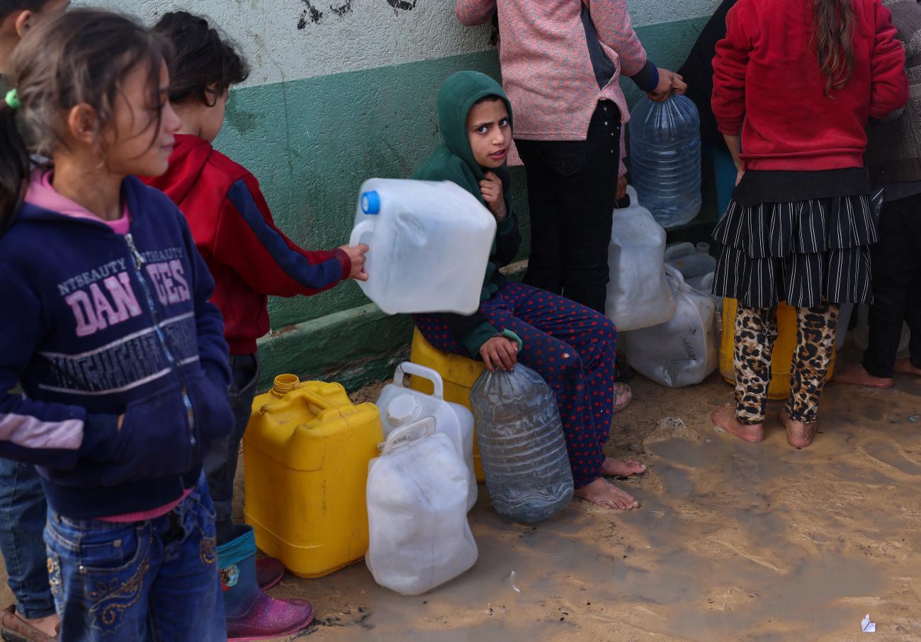 Palestinian children wait to collect drinking water amid shortages.