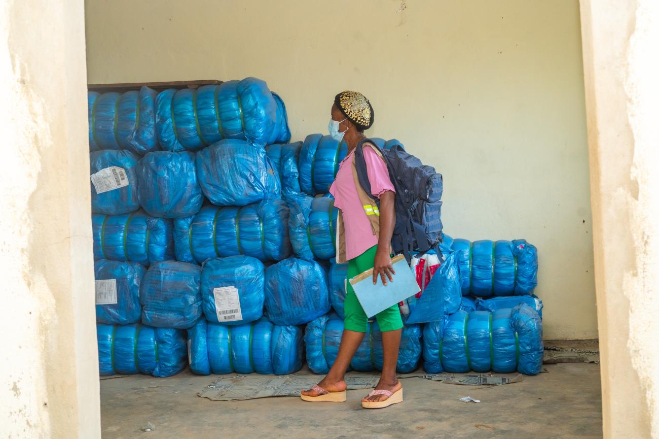 A woman stands in a storage warehouse for dual AI insecticide-treated mosquito nets