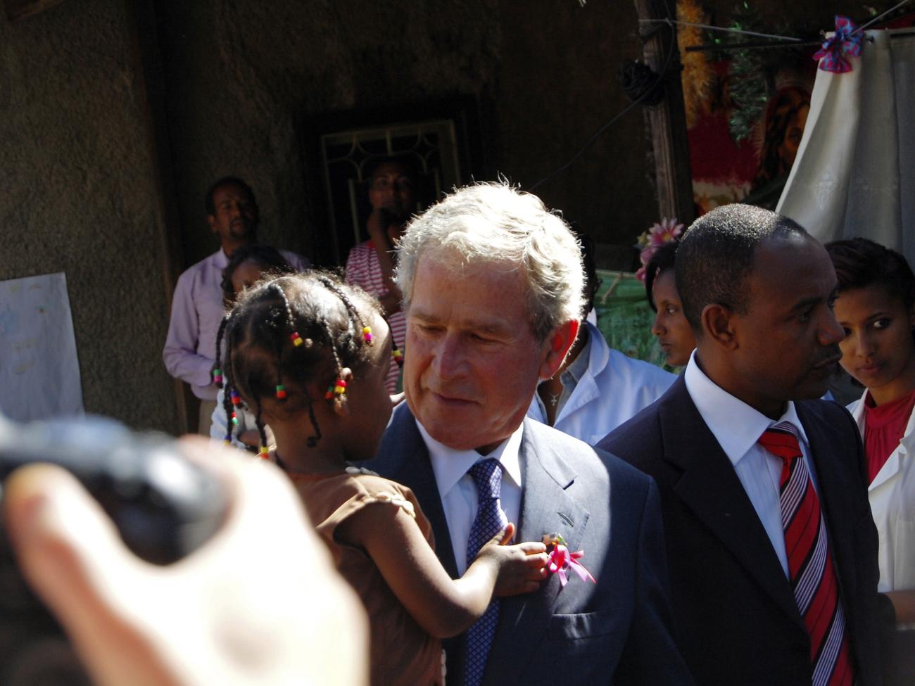 Former U.S. President George W. Bush carries an Ethiopian child whose mother is receiving HIV treatment through programmes funded by the President's Emergency Plan for AIDS Relief (PEPFAR), after arriving with his wife former First Lady Laura Bush in Addis Ababa, Ethiopia, December 4, 2011