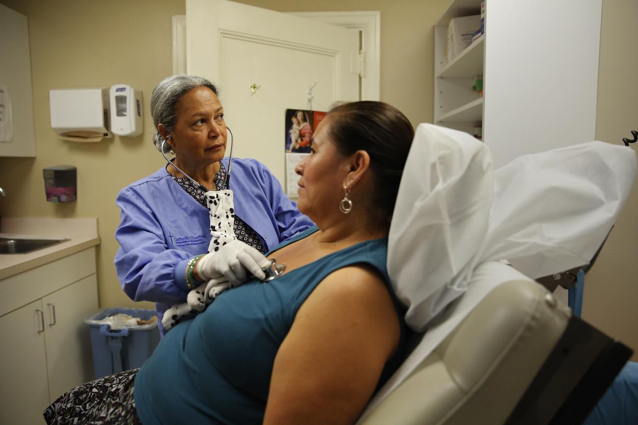 A nurse listens to a client's chest at the Spanish Catholic Center agency.