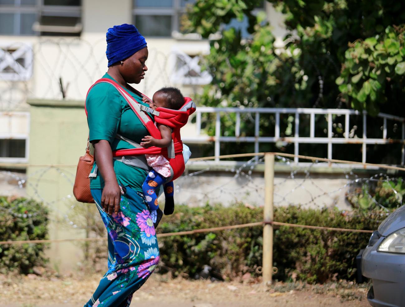A mother carries her baby in a strap carrier bag outside the Wuse general Hospital in Abuja, Nigeria January 26, 2022. 