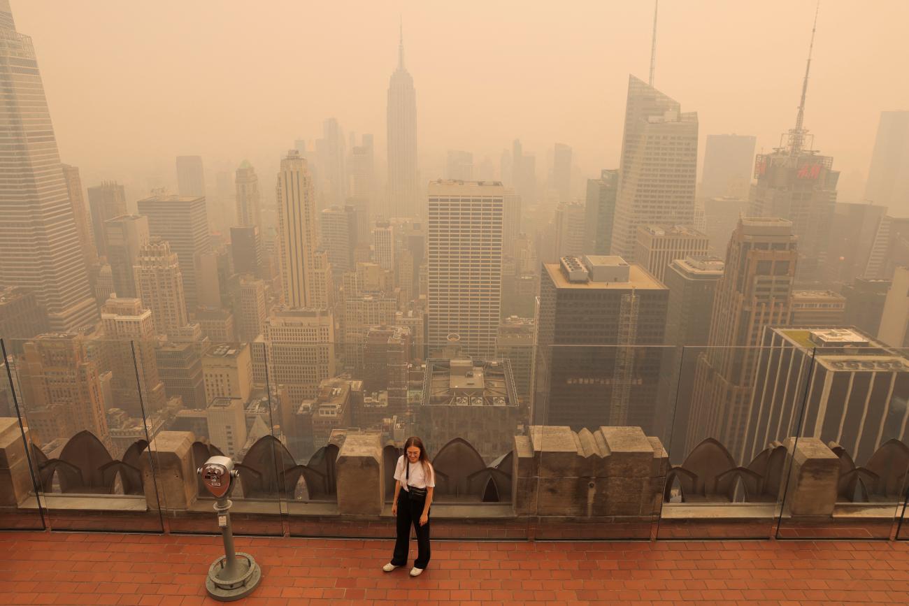 A person visits the top of the Rockefeller Center, as haze and smoke caused by wildfires in Canada hang over the Manhattan skyline.