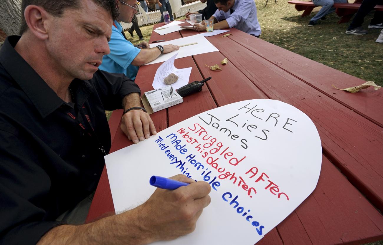 Peer 1 client James J. writes an epitaph for himself on a mock tombstone during a blind faith trust exercise in Denver September 15, 2015.