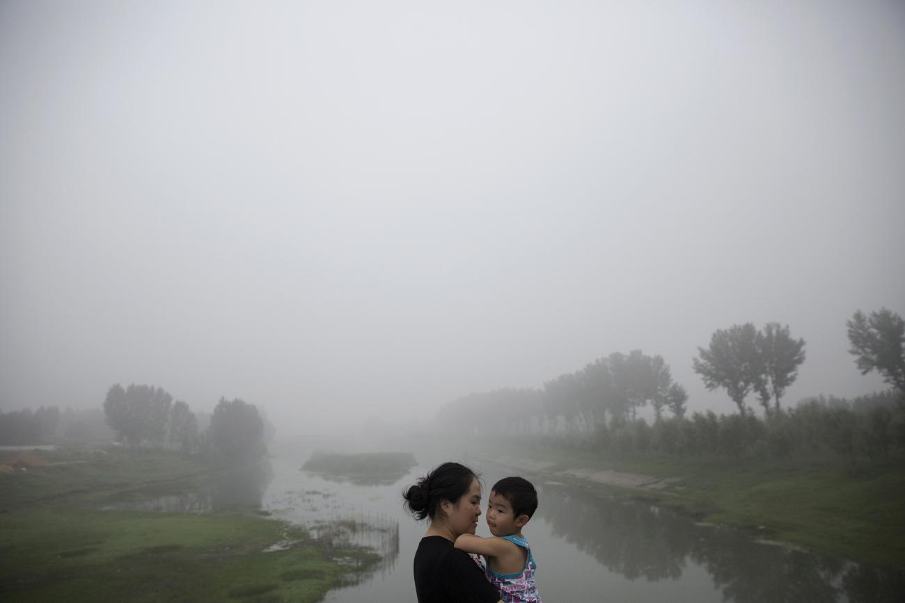 A woman holds a child as travelers wait for the highway from Beijing to China's Hebei Province to reopen on a heavily polluted morning, on August 3, 2015.