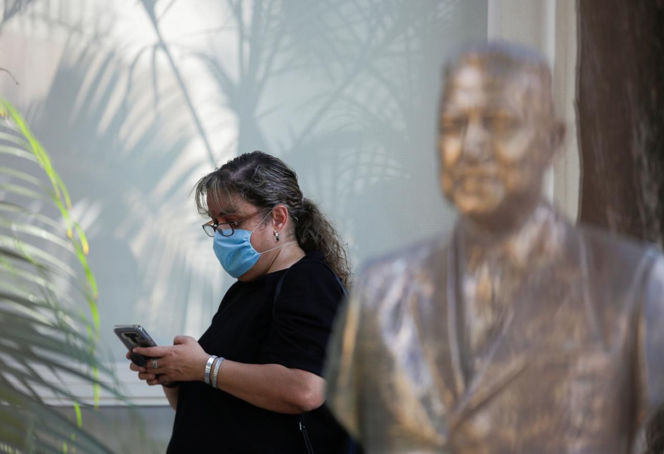 A woman uses a cellphone as she waits for information from a nursing house, where people have been infected by the COVID-19 according to local media, in Guadalupe, Mexico, on May 6, 2020.