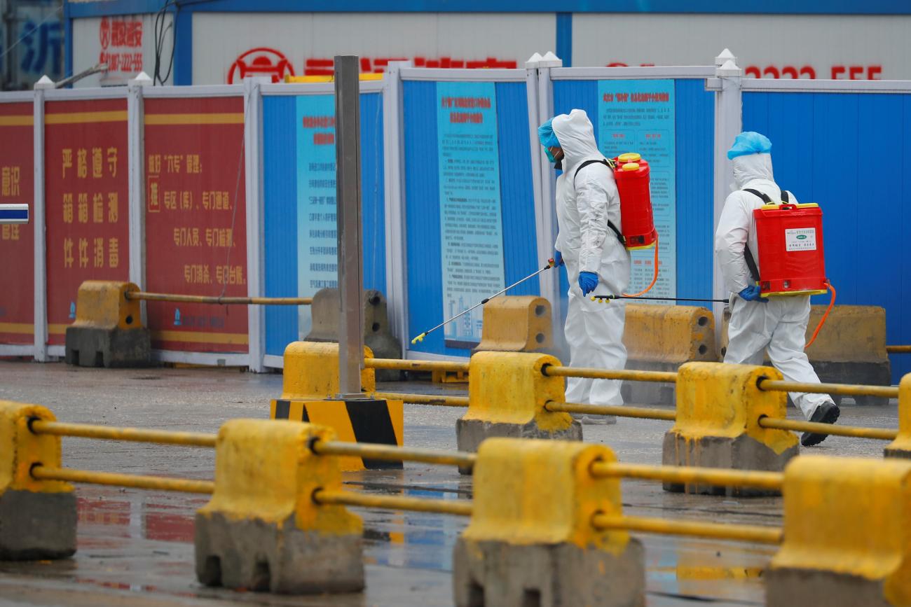 Workers in PPE spray the ground with disinfectant during a visit of World Health Organization team tasked with investigating the origins of COVID-19, in Wuhan, China, on January 31, 2021. 