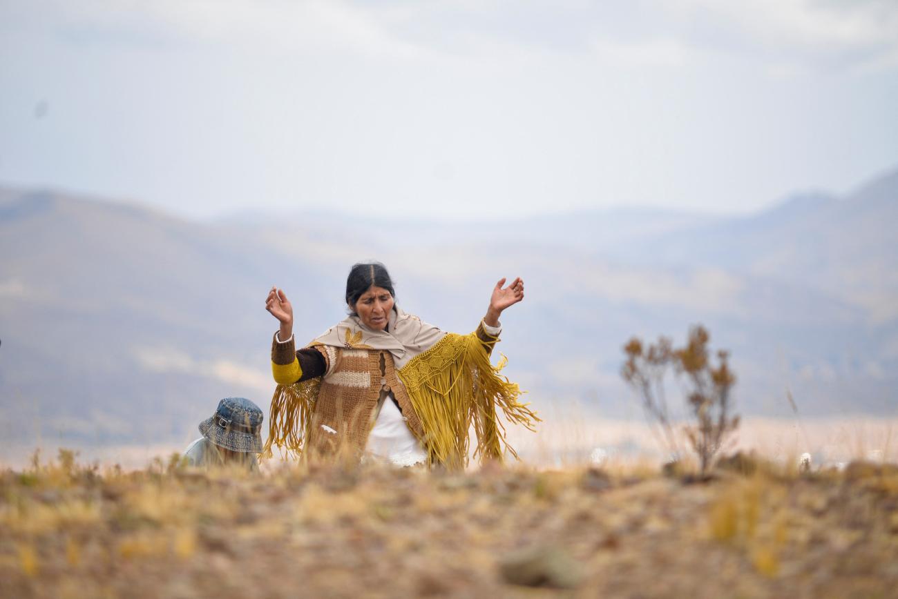 An Indigenous woman raises her hands in prayer asking for rain in the Lloko Lloko community, in Tihunaco, Bolivia, on November 23, 2022.