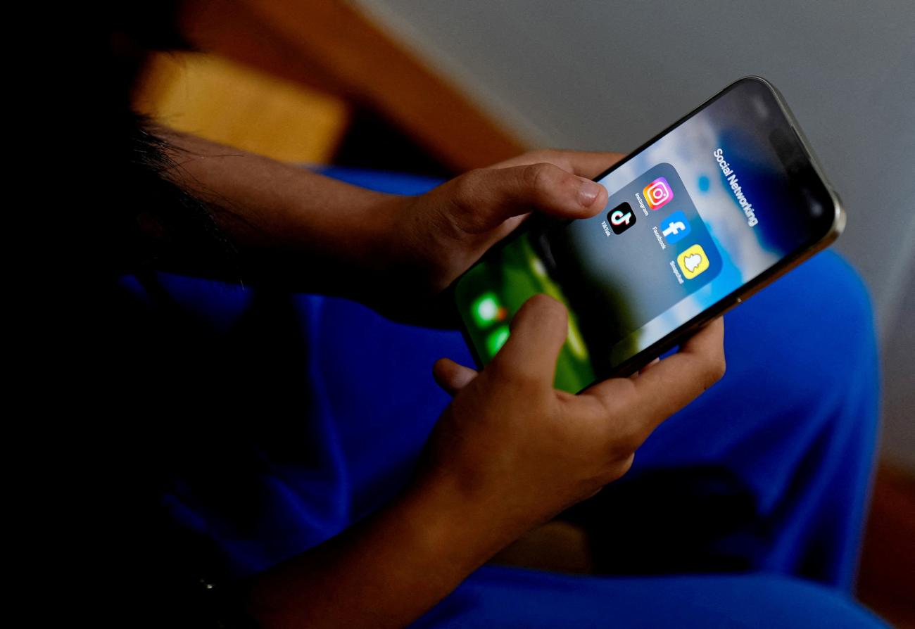 A high school student poses with her mobile showing her social media applications. in Melbourne, Australia, on November 28, 2024.