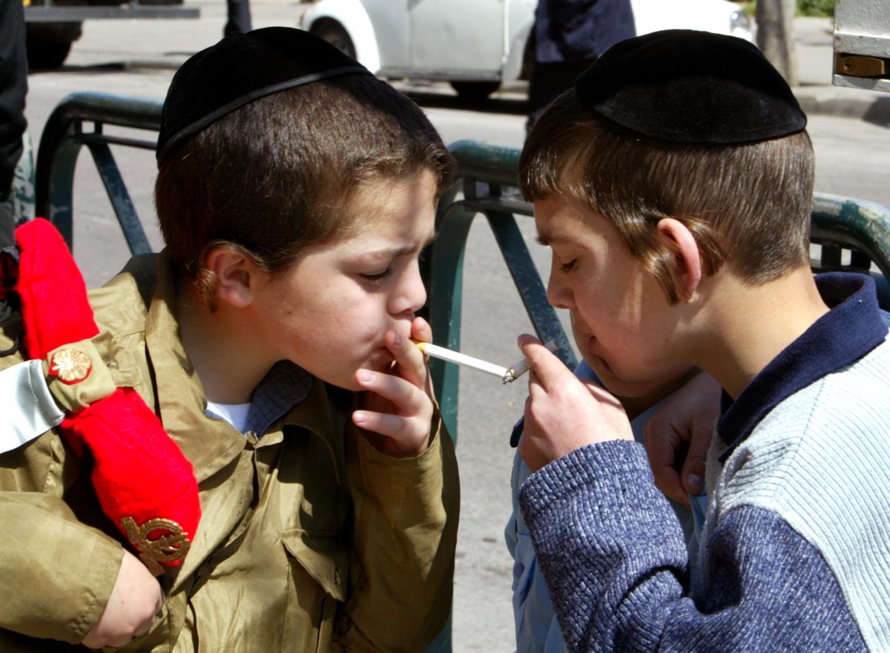 Young Ultra-Orthodox Jewish boys, one boy dressed up as an Israeli soldier (L) light cigarettes during Purim carnival celebrations in Jerusalem March 8, 2004. 