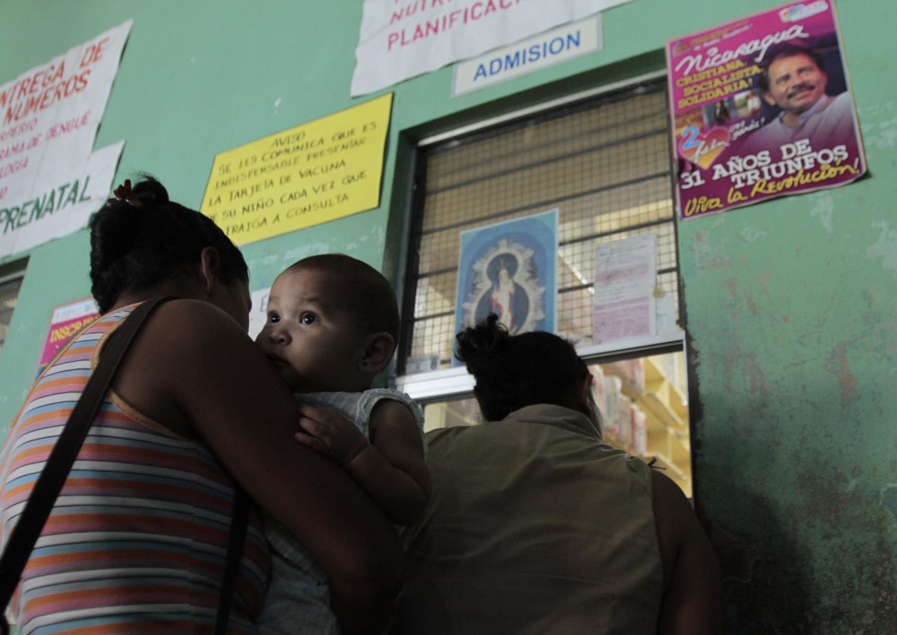 A mother carries her child while they wait to receive a pneumococcal vaccination, in Managua, Nicaragua, on January 13, 2011.