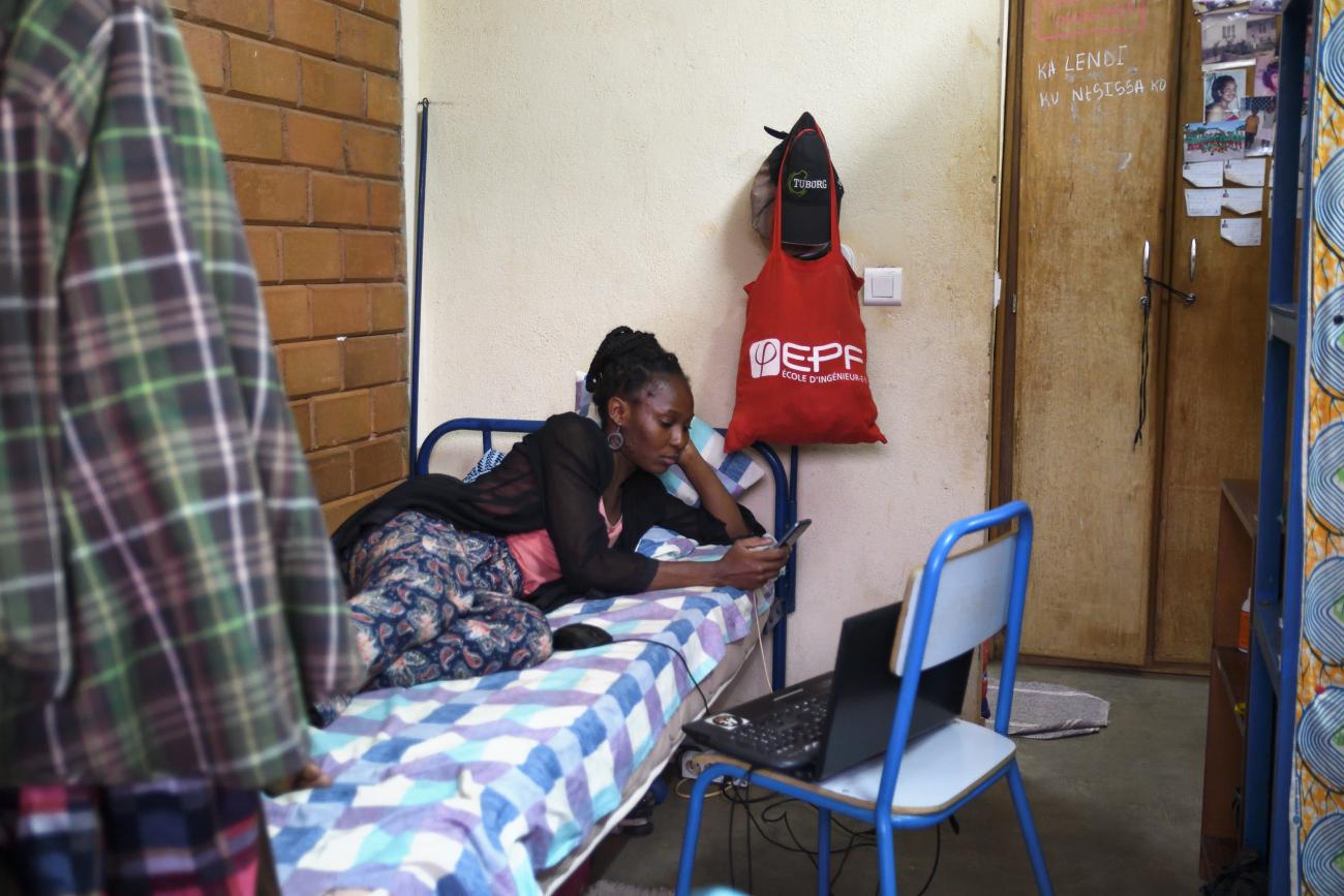 A student watches a movie on her computer as she lies on her bed, in Ouagadougou, Burkina Faso, on April 1, 2020.