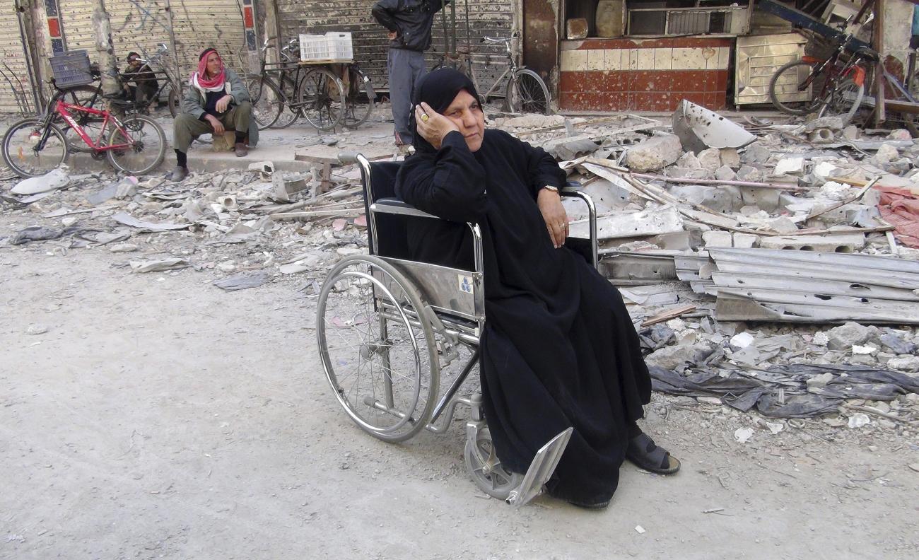 A Palestinian woman waits to receive humanitarian aid distributed by U.N. Relief and Works Agency (UNRWA) at al-Yarmouk camp, south of Damascus, February 24, 2014. 