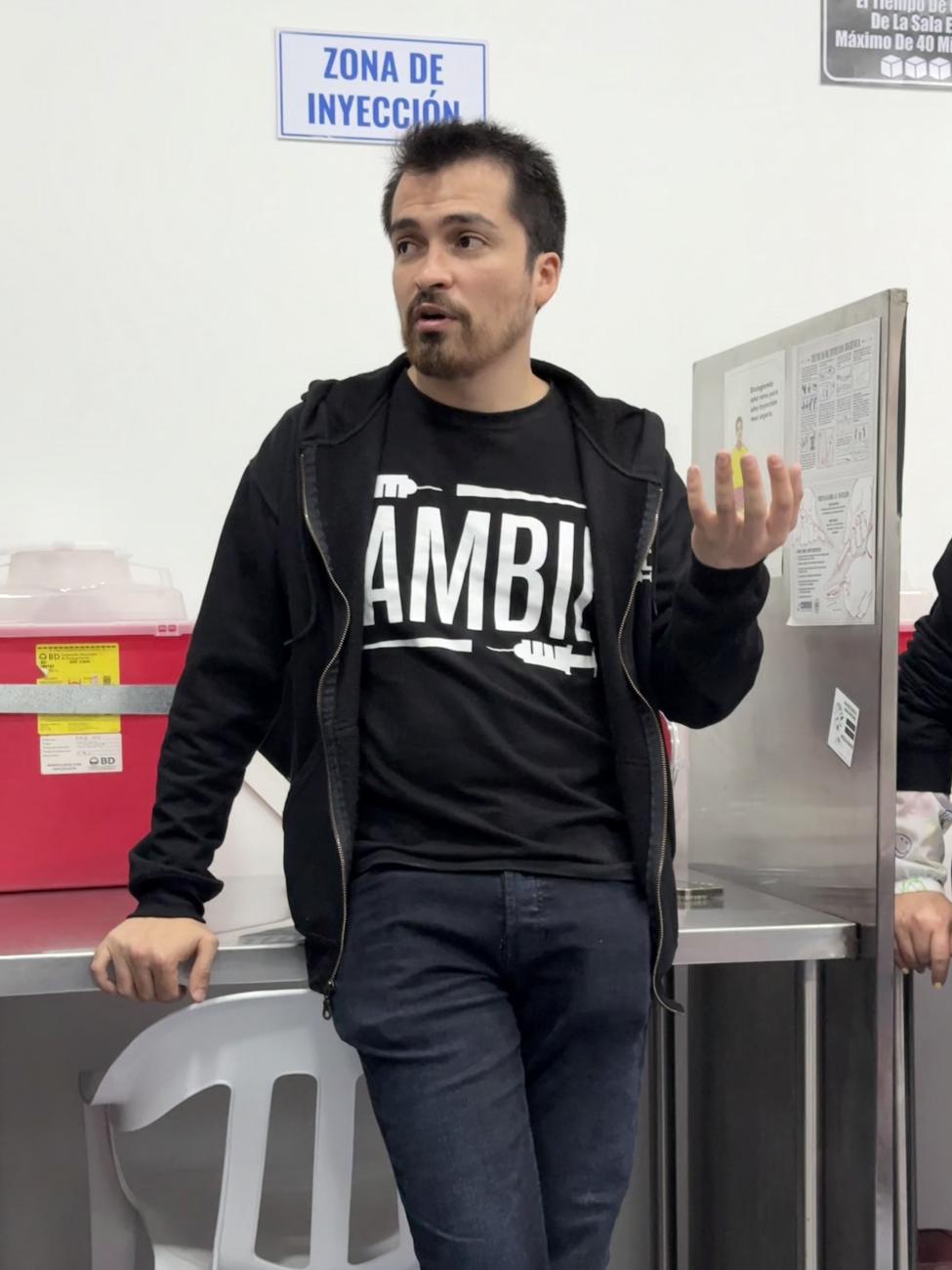 Daniel Rojas, a psychologist and Cambie's coordinator, stands in front of a needle disposal box and injection booth at Cambie in Bogota, Colombia.