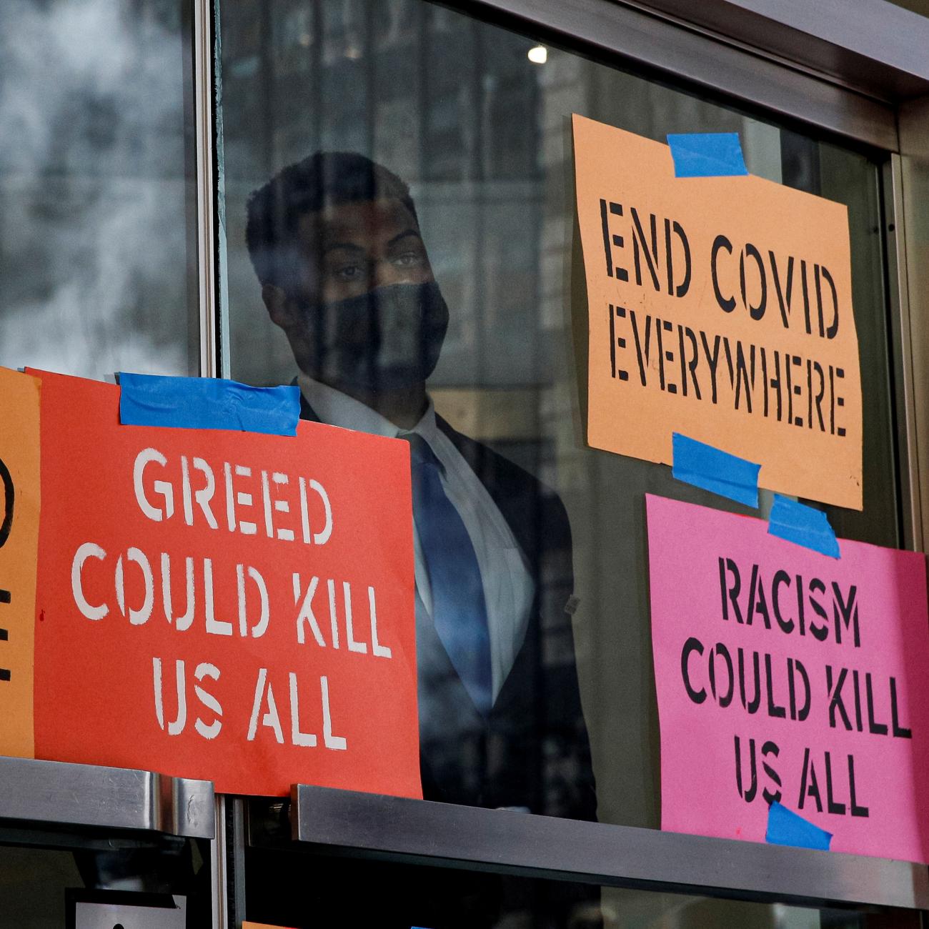 A security person looks out from the entrance to the Pfizer World Headquarters as activists rally for global access to the COVID-19 vaccine, in New York, July 14, 2021. 
