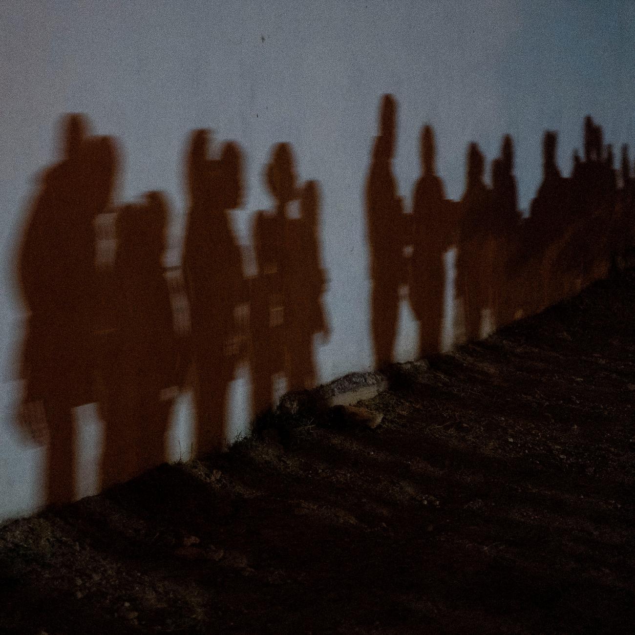 Shadows on a wall show asylum-seeking families as they queue up to be processed by the U.S. Border Patrol after crossing the Rio Grande River from Mexico, in Roma, Texas on August 12, 2021.