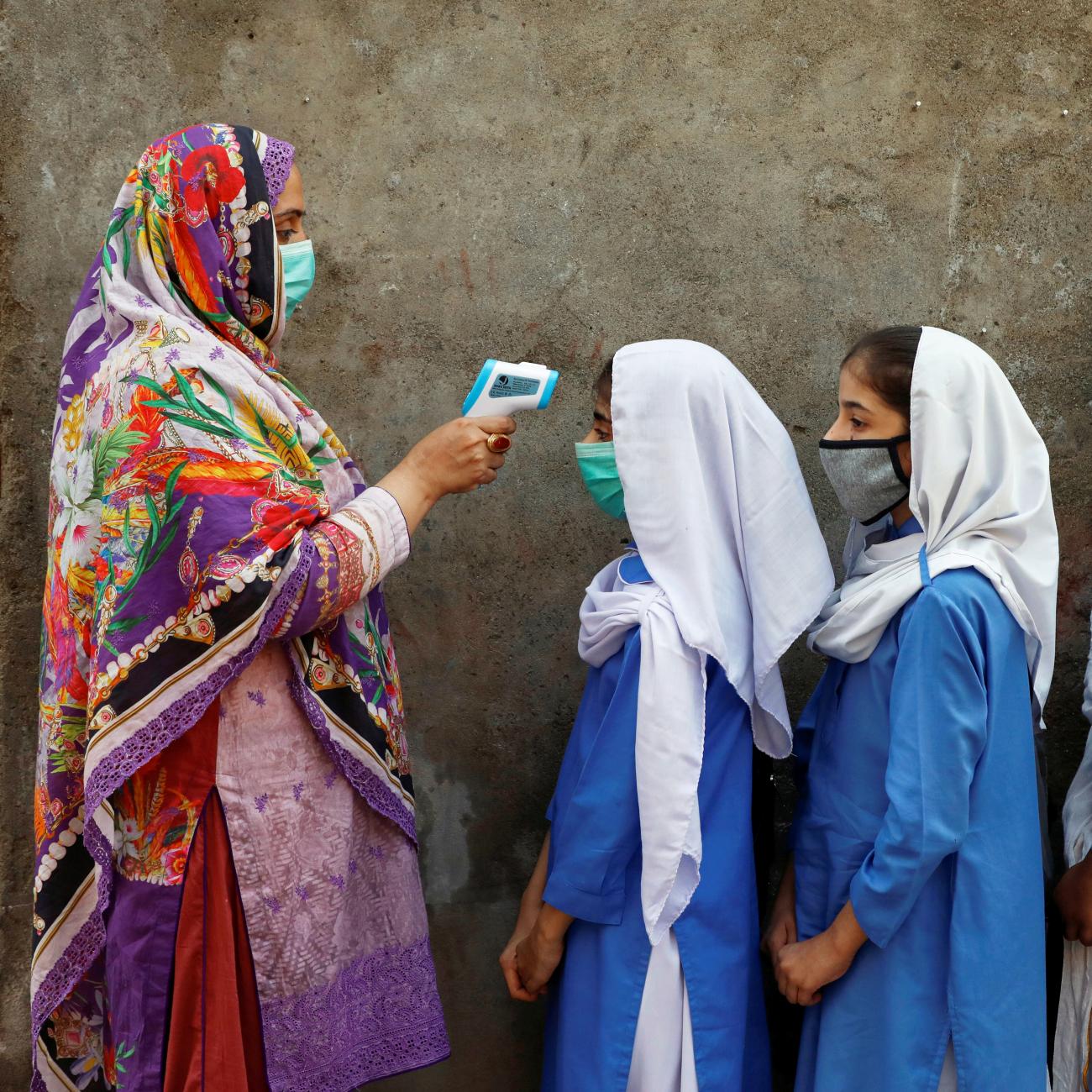 Students wear protective face masks as they have their temperature checked before entering a class, after the government allowed the reopening of schools from grade six to eight amid the coronavirus disease (COVID-19) pandemic, in Peshawar, Pakistan September 23, 2020.