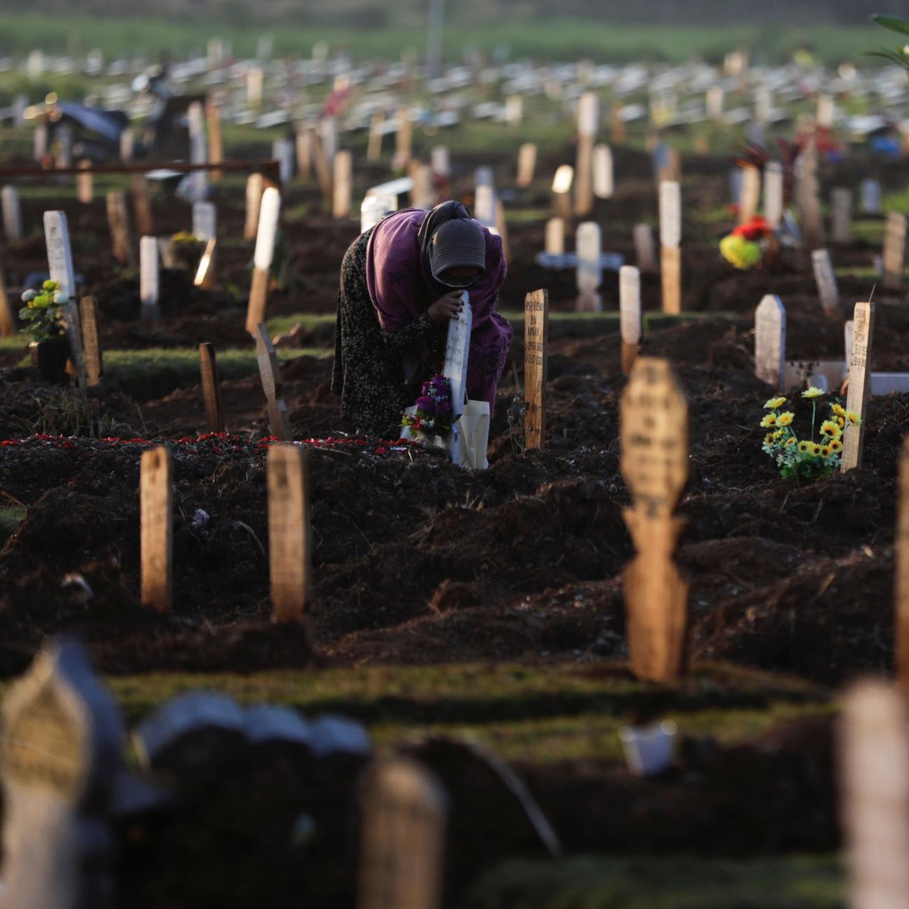 A woman mourns at the grave of her husband who passed away due to COVID-19, at a burial area provided by the government for COVID-19 victims as the country reports a record daily number of COVID-19 deaths, in Bekasi, Indonesia, on July 27, 2021