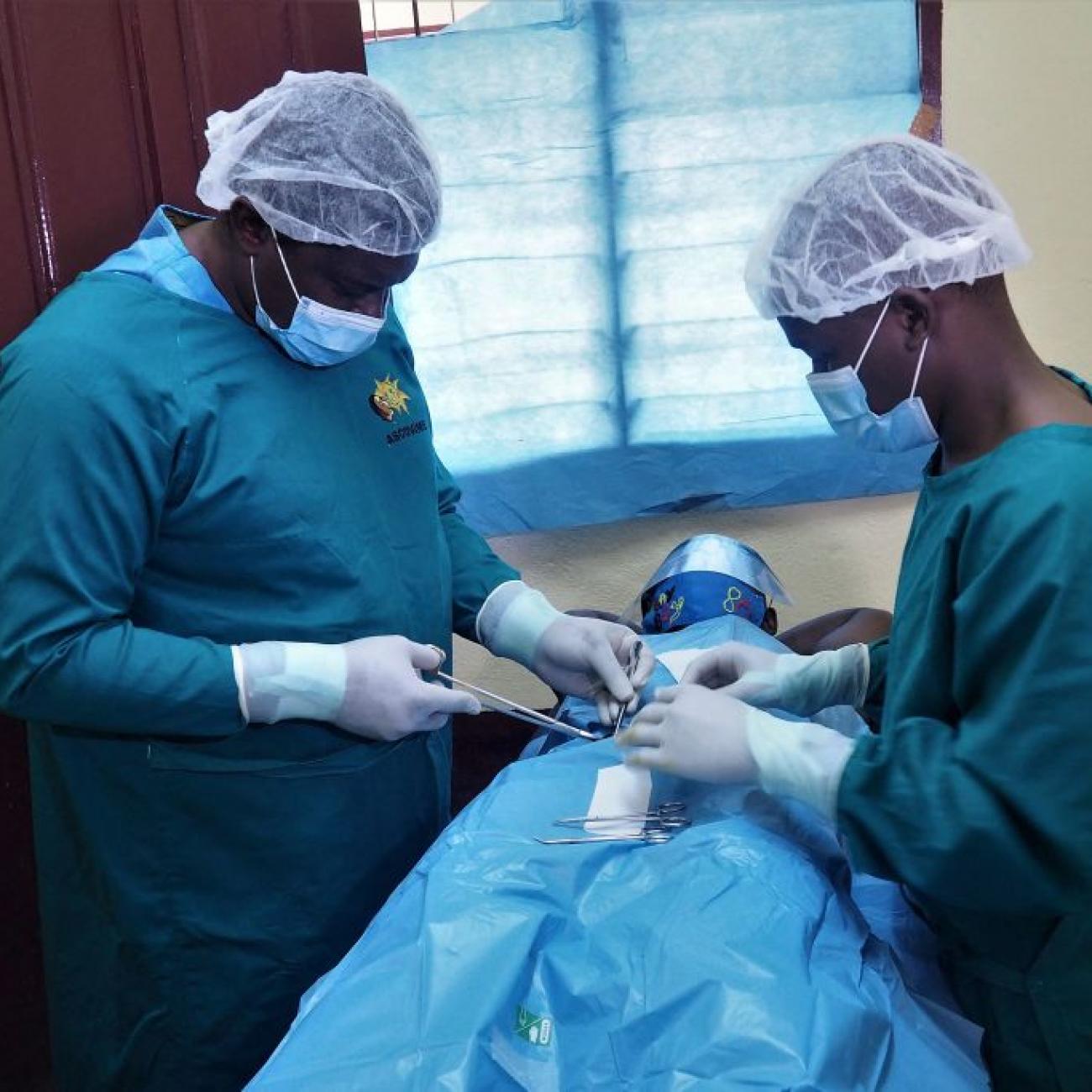 Doctor Georges Bwelle (L), head of the visceral surgery department at the Yaounde Central Hospital, and one of his colleagues operate on a patient at the Nkongsamba prison in Nkongsamba, Cameroon, on July 17, 2021. 