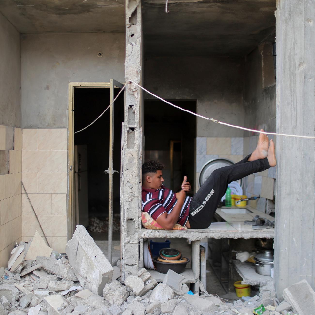  A young man uses his phone is a destroyed building