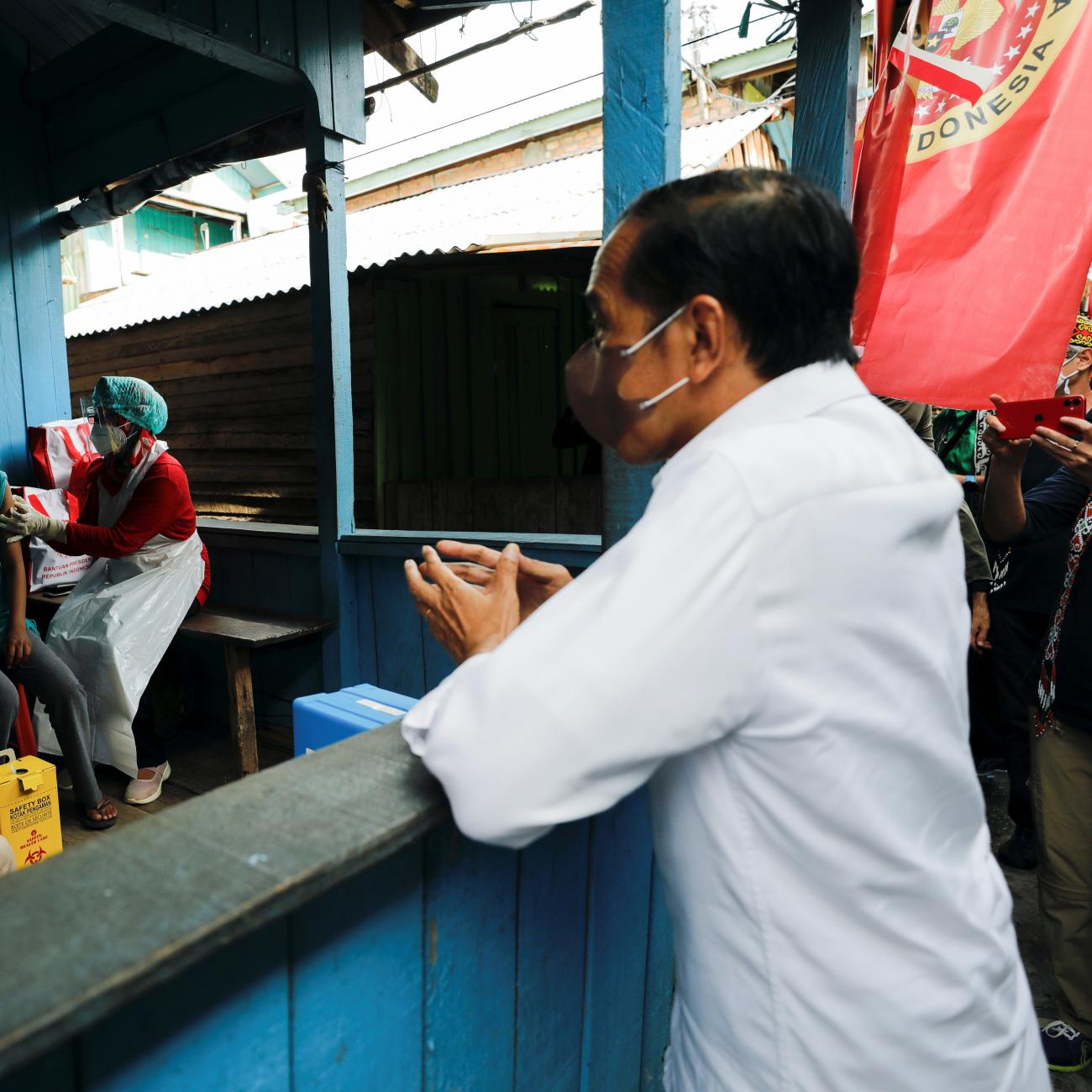 Indonesian President Joko Widodo talks with locals during a door to door mass vaccination program against coronavirus disease