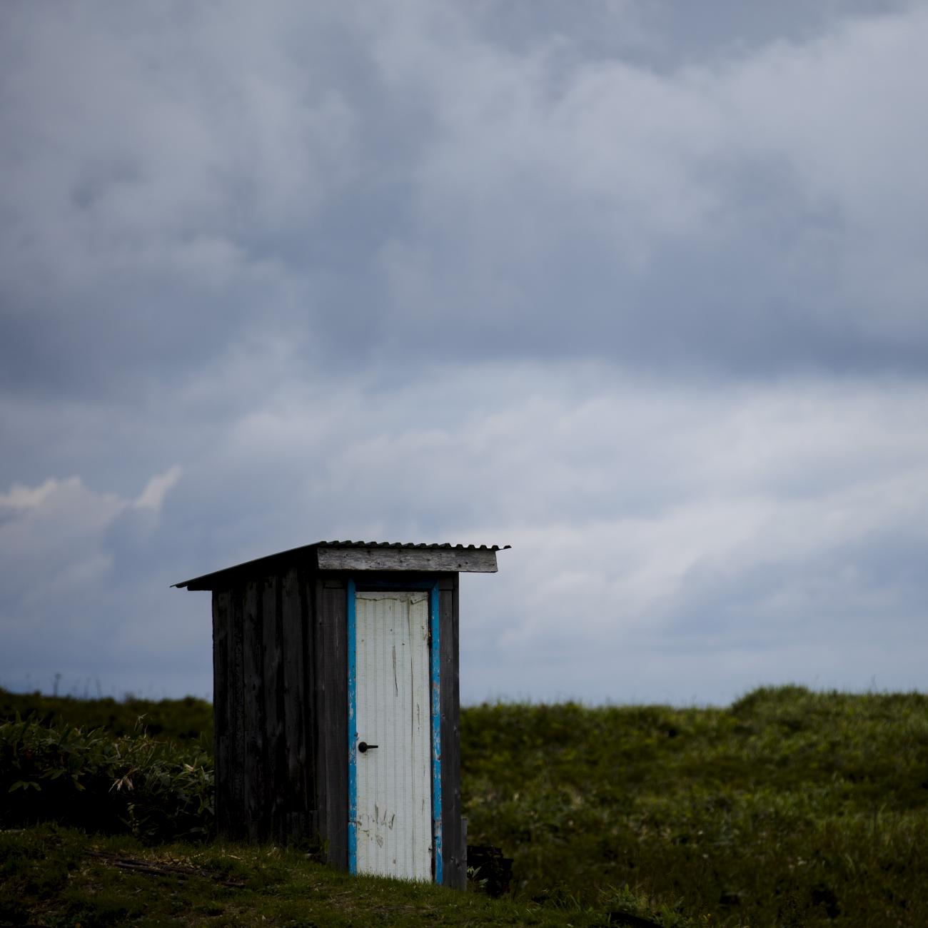 A hut is seen against a cloudy field