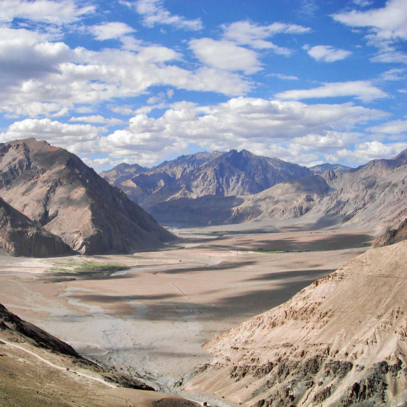 White clouds in a bright blue sky above the Himalaya Mountains and Zanskar Valley