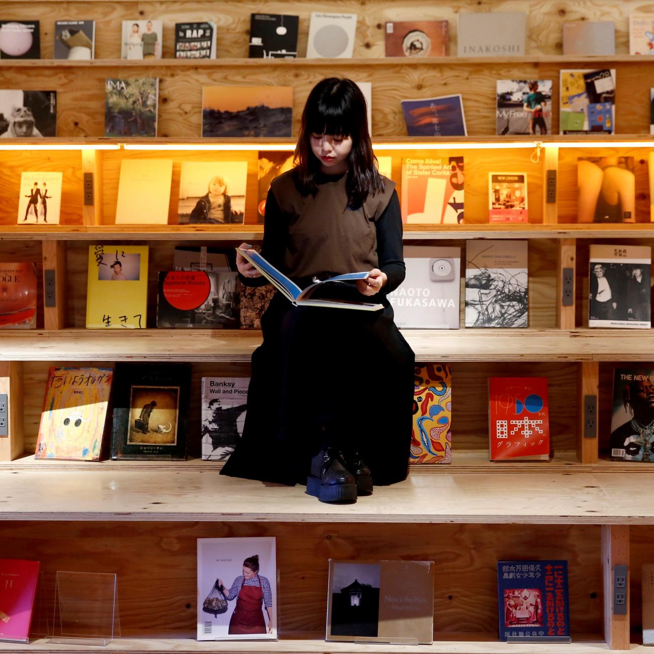 A woman reads a book at the Shinjuku branch of Book and Bed, an accommodation combined with book cafe where guests can sleep in hidden bunks built into a large bookshelf, during a photo opportunity in Tokyo, Japan September 14, 2018.