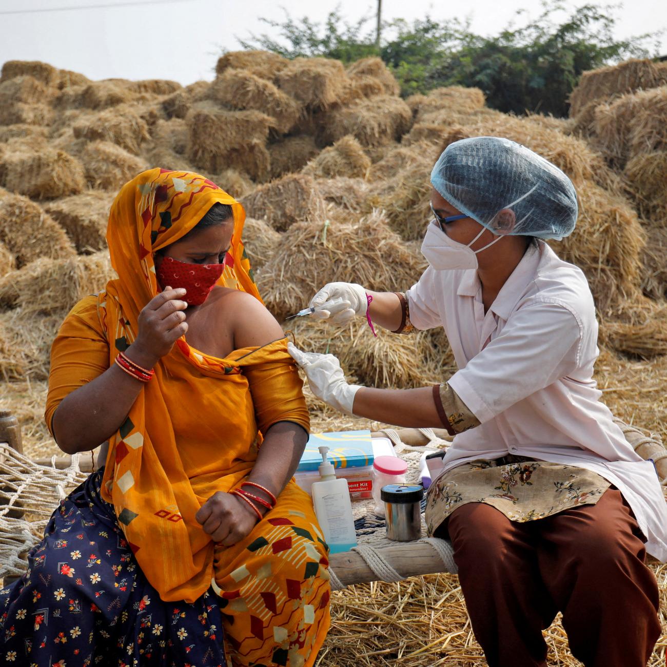 Jabuben Bharwad, 30, receives a dose of COVISHIELD vaccine against COVID-19, that's manufactured by Serum Institute of India, while working in a field during a door-to-door vaccination drive at Mahijada village on the outskirts of Ahmedabad, India, December 15, 2021