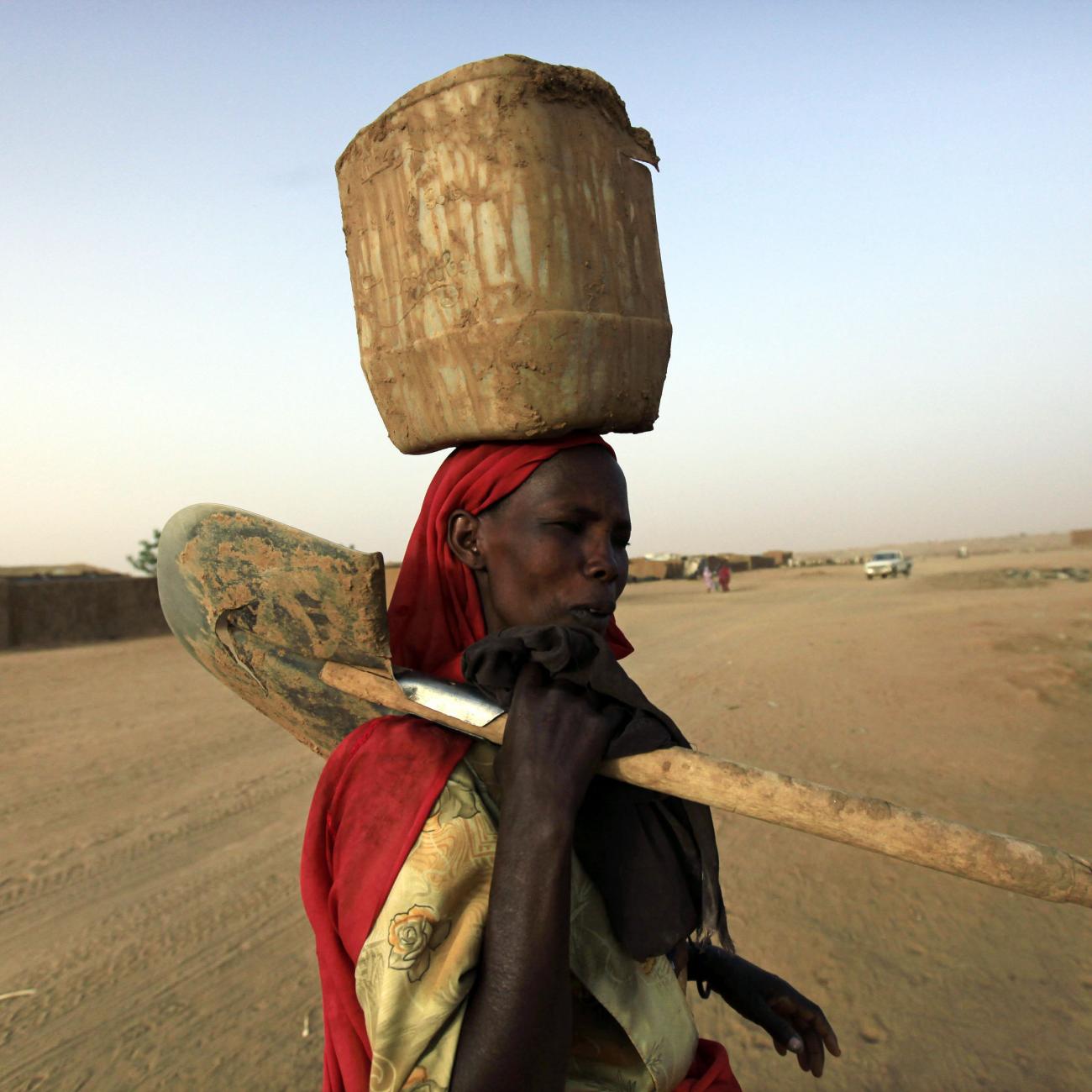  displaced Sudanese woman carries a container and shovel at the Abu Shouk IDP (internally displaced persons) camp in Al Fasher, northern Darfur April 8, 2010