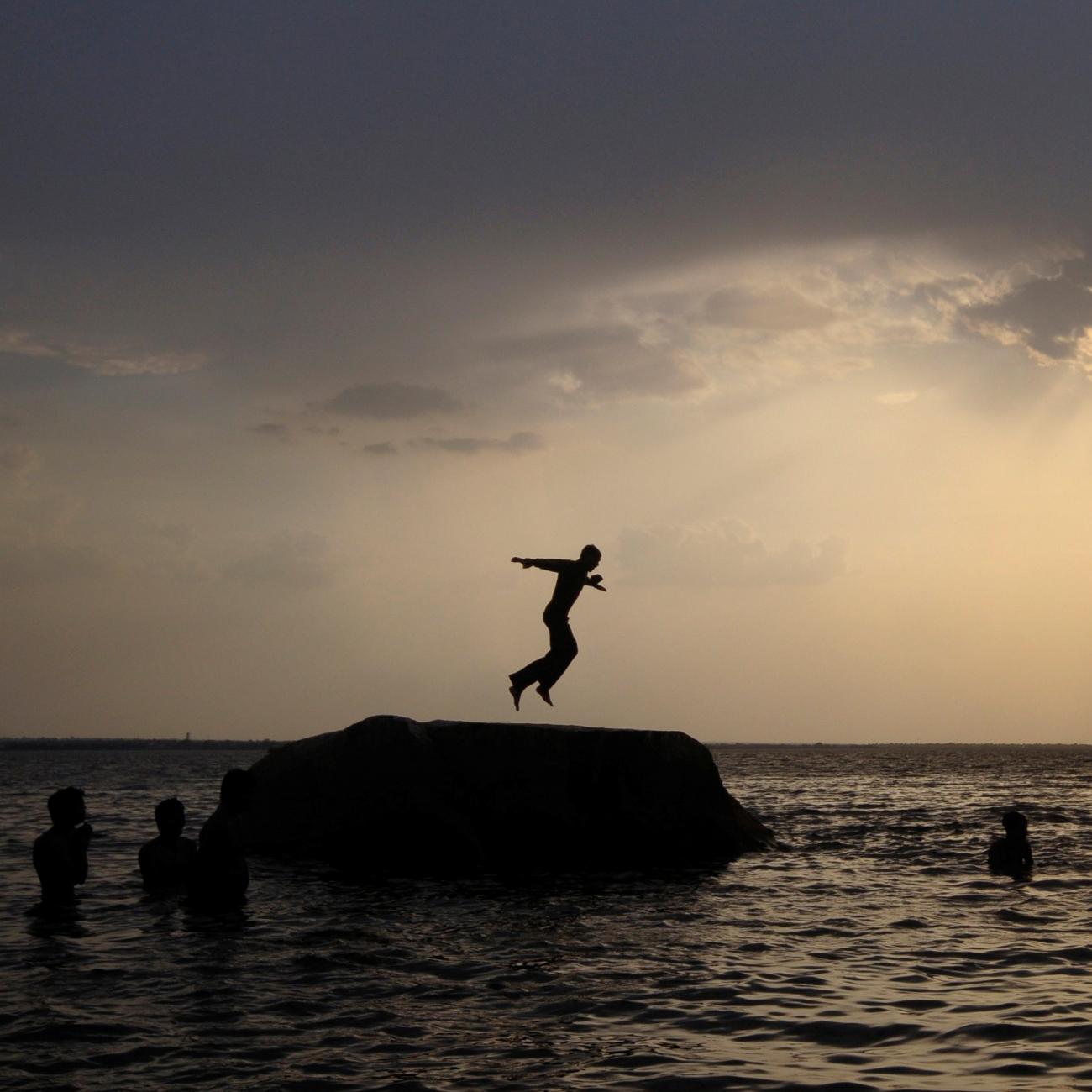 As the sun sets, a boy prepares to jump off a rock into the waters of the Osman Sagar Lake near the southern Indian city of Hyderabad May 29, 2011. 