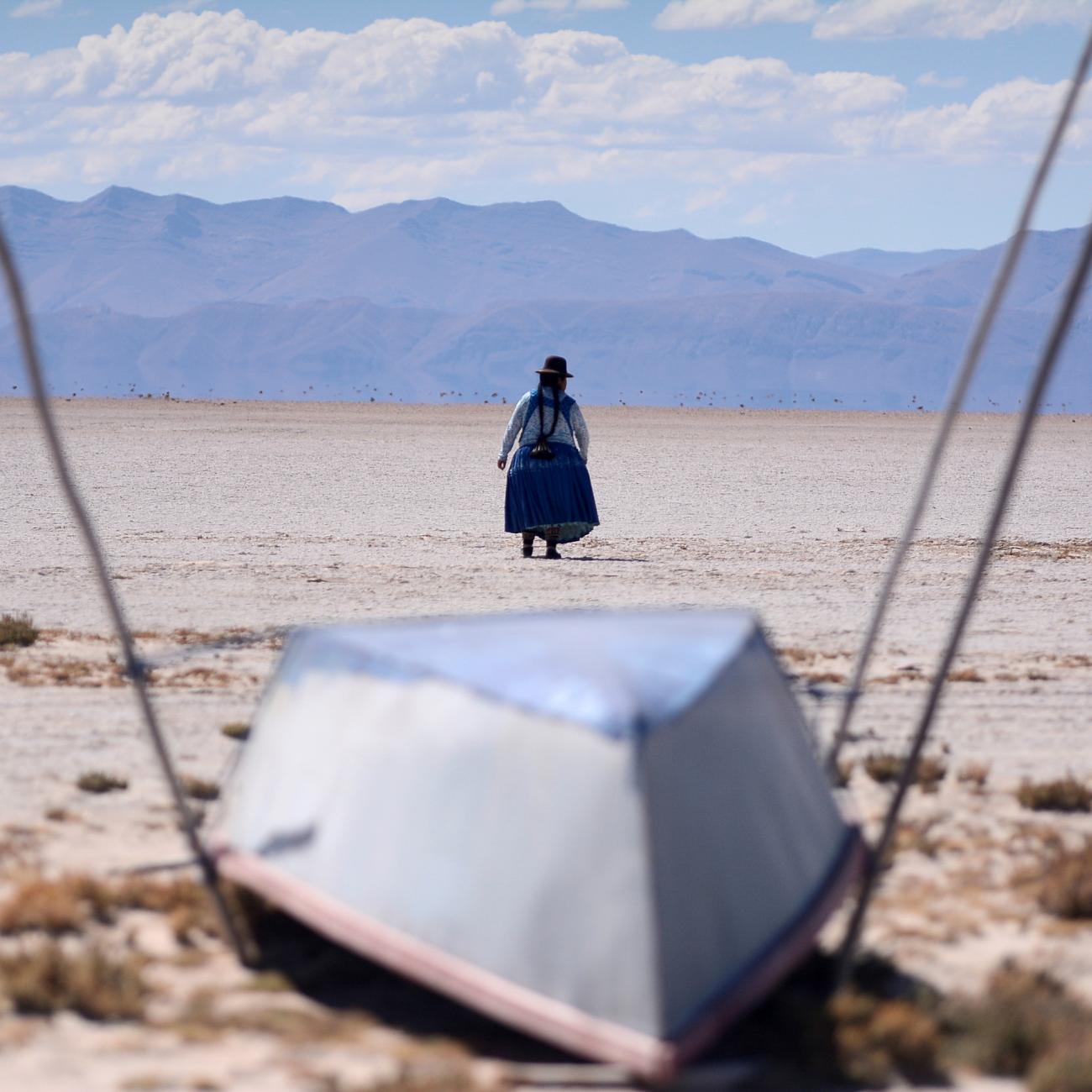 Cristina Mamani walks in dried up Lake Poopo, Bolivia—brought on by a warmer, drier climate, say local residents and scientists. Photo taken July 24, 2021. 
