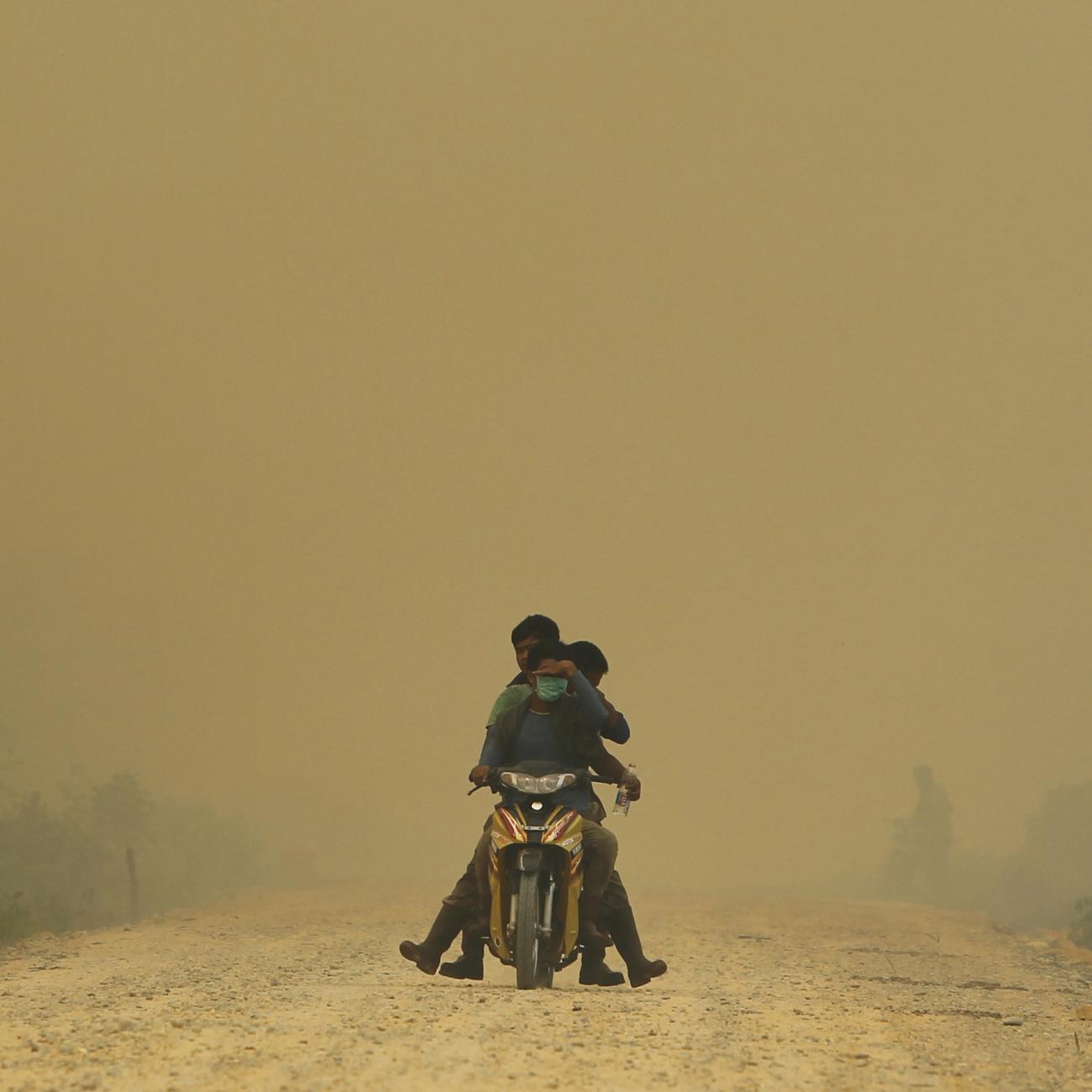 Villagers ride a motorcycle in a haze hit Dumai, in Indonesia's Riau provinc